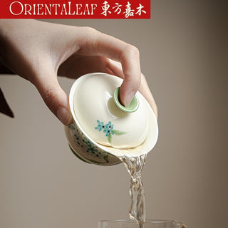 A celadon gaiwan that is pouring tea.