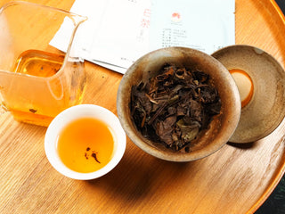 2018 sun-dried Fuding White Peony compressed tea biscuit in a complete gongfu setup, with amber tea liquor and steeped leaves on a wooden tray.