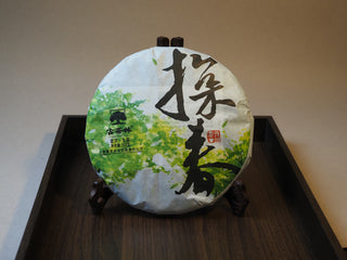 Front view of the 2019 Tan Chun Lincang ancient tree raw puerh tea cake in its traditional paper wrapper.