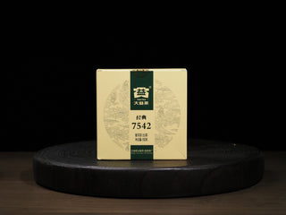 Front view of the 2020 Dayi 7542 raw puerh tea 150g paper box packaging on a dark wooden tray.