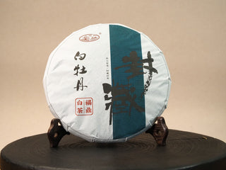 2020 Fuding Sun-Dried White Peony 350g cake — front paper wrap with traditional calligraphy, displayed on a wooden tea stand.