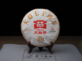 Front view of 2022 Dayi 7572 ripe puerh tea cake Batch 2201 with classic paper wrapper on a display stand.

