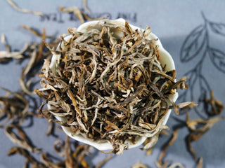 Dry leaves of Special Grade Ailao Golden Bud Yunnan Yellow Tea showing downy white hairs.
