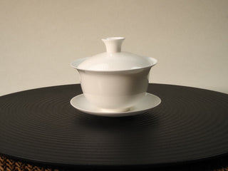 Egg-shell porcelain gaiwan pure white three-piece set with lid, bowl and saucer on a dark round tea mat