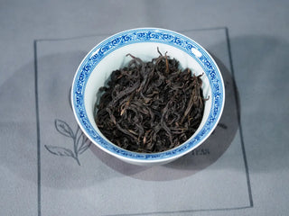 Floral Wuyi Rock Oolong Tea – Jin Guanyin (204 Cultivar) dry tea leaves displayed in a gaiwan, showing tight dark-green strips and floral aroma potential.