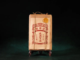 Front view of Jingyang Golden Flower Fu Brick Tea with handcrafted cowhide paper packaging, tied with hemp rope and sealed with wax, showcasing traditional Chinese dark tea craftsmanship.