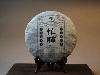 Front view of 2022 Mangfei Mountain raw Pu-erh tea cake in traditional paper wrapper