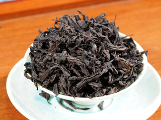 Traditional Da Hong Pao dry tea leaves in a white porcelain gaiwan, heavy fire roasted.