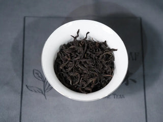Dry loose leaf Wuyi Rock Oolong tea, Huang Guan Yin 105 cultivar, showing dark curled leaves in a white gaiwan.