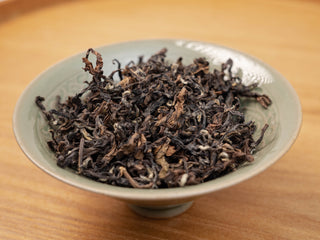 Premium Yunnan Golden Empress Oolong dry tea leaves in a ceramic bowl