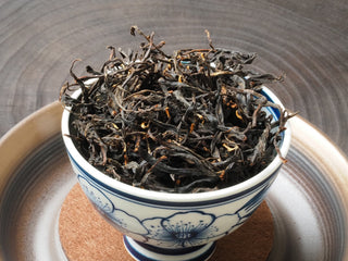 Yunnan Shaken-Leaf Black Tea dry leaves displayed in a blue and white porcelain tasting cup.