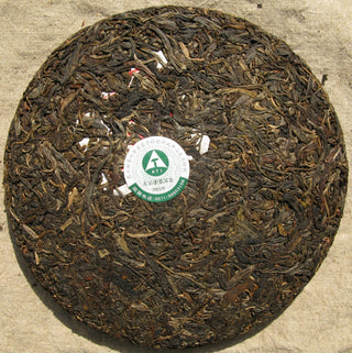 Surface of 20-year aged Mengku Spring Tips raw Pu-erh cake showing dark aged leaves.
