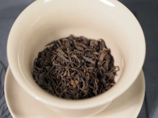 Loose leaf 2013 Aged Liubao Tea placed in a white ceramic Gaiwan, displaying the fermented dark tea texture ready for Gongfu brewing.