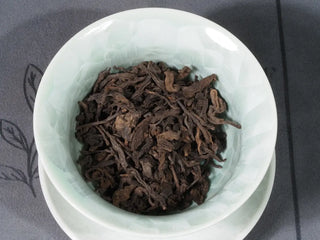 Close-up of 2014 Aged Liubao Dark Tea dry leaves in a gaiwan, ready for brewing, emphasizing the Betel Nut Aroma.