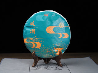 Front view of 2021 Dayi Guanchao Raw Puerh Tea Cake Batch 2101 featuring the elegant teal and golden tide design paper wrapper.
