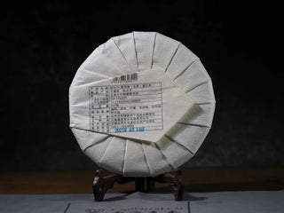 Back view of Ancient Arbor Harmony Raw Pu-erh Tea cake showing detailed product label and Yunnan origin.