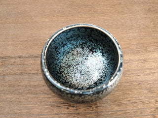 Front-rim view of a Bu Dao Weng sky eye oil spot Jianzhan bowl, showing the slightly rounded lip and dense silver crystals at the edge.