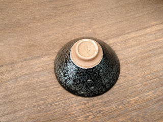 Base of a Da Dou Li sky eye oil spot Jianzhan bowl placed upside down, showing the unglazed foot ring with a small impressed makers mark and exterior silver oil-spot crystals.