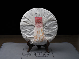 Back view of the wrapped 2022 Dayi 7572 ripe puerh tea cake, showing the folded paper packaging.
