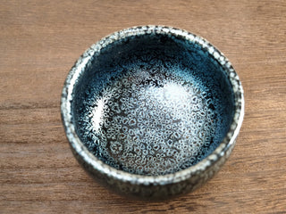Close-up top view of a Jiang Jun Bei Sky Eye Jianzhan tea bowl showing the interior densely covered with silver oil-spot crystals.