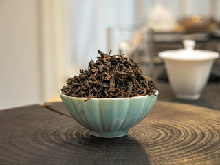 A heap of 2022 Mang Fei loose leaf shou puerh tea leaves piled in a celadon bowl.
