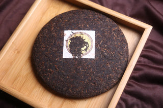 Unwrapped premium shou puerh tea cake showing fine golden buds and high-grade gongting tea leaves.