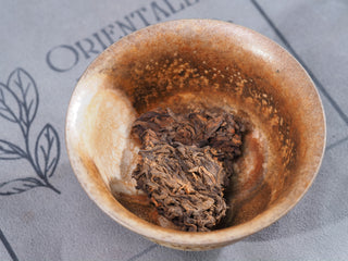 Close-up of dry Ripened Puerh Tea Nuggets in a ceramic gaiwan, highlighting the compressed tea texture.
