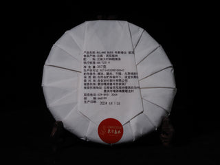 Back view of the Sheng Bulang Buds Puerh cake showing traditional Chinese paper wrapping fold details.