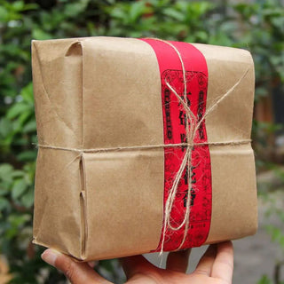 Hand-held view of the eco-friendly paper wrapped Yiwu premium rose scented ripe tea.