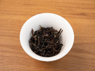 Close-up of Yunnan Golden Empress Oolong dry leaves in a white tasting cup