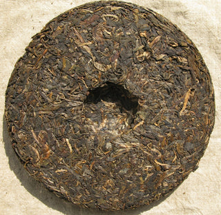 The back view of a 2006 Mengku Rongshi raw Pu-erh cake showing the compression dimple.