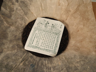 Jing Chang Hao Mengsong Autumn Harvest 2013 raw Pu-erh cake with illustrated green inner label, unwrapped from Dai mulberry paper