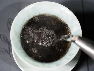 The process of rinsing (washing) the 2014 Betel Nut Aroma Liubao Dark Tea, with hot water being poured to awaken the aged tea.