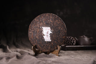 Unwrapped 2019 Bojun Ripe Pu-erh 500g cake from above, dark fermented leaves with golden buds. (inferred)