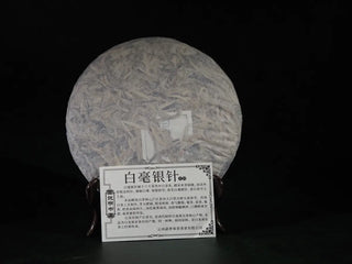 Unwrapped 2023 Jinggu Yunnan Silver Needle White Tea Cake with product info card displayed