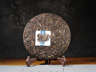 Unwrapped front view of the Ancient Arbor Harmony Raw Pu-erh Tea cake, showing tight compression and surface texture.