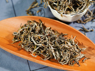 Artisan Ailao Mountain Yellow Tea buds on a wooden tea scoop for brewing preparation.