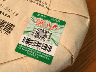 Close-up of the green anti-counterfeit label on the Bojun 7.0 cake with QR code and verification barcode.