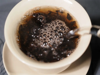 Pouring boiling water into a Gaiwan to brew 2013 Aged Liubao, awakening the leaves to release their signature sweet red bean and nutty aroma.