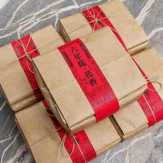 Multiple bundles of aged rose puerh tea wrapped in kraft paper, showing bulk stock availability.