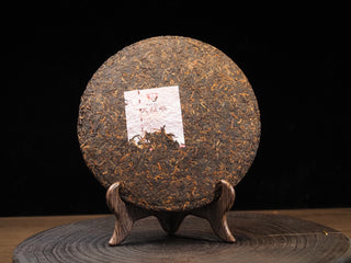 Unwrapped 2021 Dayi 7572 ripe puerh tea cake showing compressed tea leaves and the inner trademark ticket (Neifei).