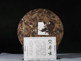 Unwrapped Yunnan High Mountain Wild Ancient Tree Shoumei White Tea Cake (2019) with product information card, front view