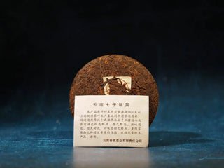 Yunnan Red Glow Ripe Pu-erh Tea Mini Cake – 100g unwrapped and displayed with the included product information card, revealing the rich dark tea leaves.