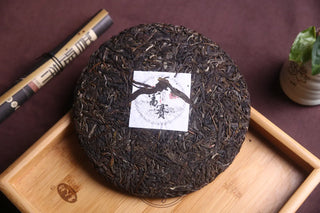 Close-up of Dark Brown Dahusai Ancient Tree Raw Pu-erh Cake on Bamboo Tray