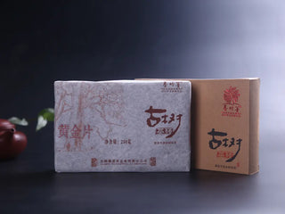 Full presentation of the Ancient Tree Golden Leaf Sheng Pu-erh Brick next to its box.