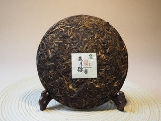 Full view of the unwrapped 2005 Lincang Sheng Pu-erh tea cake showcasing tightly compressed dark-brown aged leaves.
