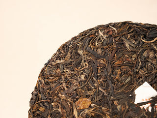 Close-up of Jing Chang Hao Bada Ancient Trees 2013 raw Pu-erh cake surface, dark green-brown leaves with golden tips