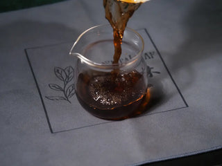 Pouring the red-brown liquor of 2014 Aged Liubao Dark Tea into a fairness pitcher (Gong Dao Bei), highlighting its rich color.