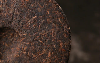 Close detail of the 2017 Bojun 500g cake surface, showing tightly pressed dark fermented leaves with golden tips, aged character.