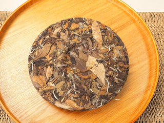 Reverse side of 2018 Fuding Shou Mei 350g compressed cake showing the texture of pressed broad leaves and stems.
